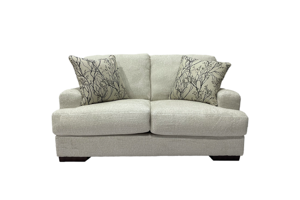 Loveseat de color beige con cojines decorativos sobre un fondo blanco. 