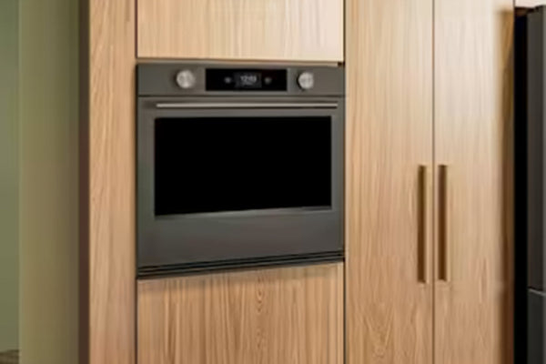 Horno empotrado de acero inoxidable con puerta de cristal negro y panel de control digital, integrado en armarios de cocina de madera de roble claro.