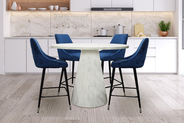 Mesa redonda con diseño de mármol blanco con cuatro sillas acolchados de color azul, con reposapiés y respaldar en una cocina moderna. 