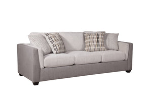Vista lateral de sofá con acolchado crema y gris claro con cuatro cojines decorativos con patrones, todo sobre un fondo blanco. 