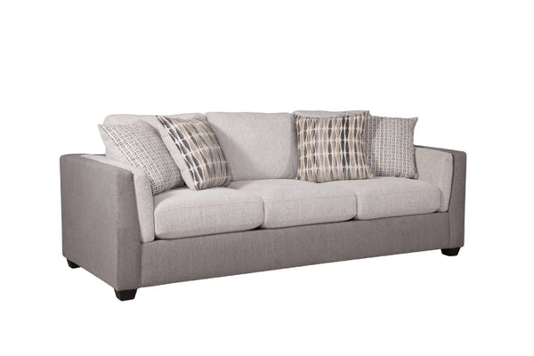 Vista lateral de sofá con acolchado crema y gris claro con cuatro cojines decorativos con patrones, todo sobre un fondo blanco. 