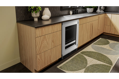 Una nevera para vinos empotrada bajo la encimera, con puerta de mueble con acabado de madera y encimera negra, en un entorno de cocina moderno.
