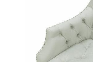 Vista cercana de brazo de silla de acento color crema con respaldo capitonado y detalles de tachuelas, sobre un fondo blanco. 