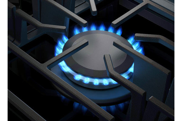 Primer plano de un quemador de estufa de gas con una rejilla de metal oscuro y una llama azul brillante encendida debajo de la tapa del quemador.