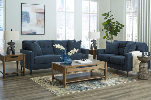 Conjunto de sofás azules en una sala de estar con mesa de centro y mesas auxiliares de madera.