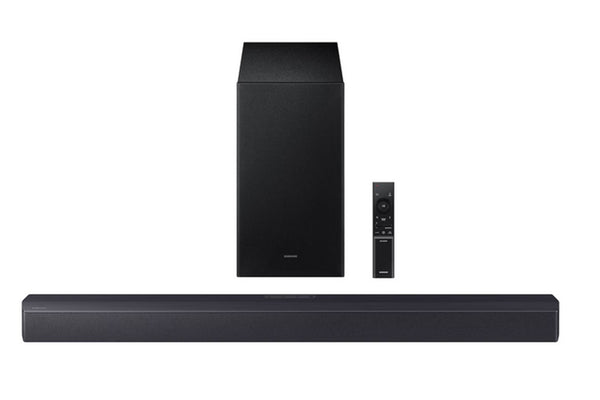 Barra de sonido negra con subwoofer y control remoto sobre fondo blanco. 