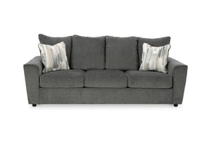 Sofá gris con cojines estampados sobre fondo blanco.