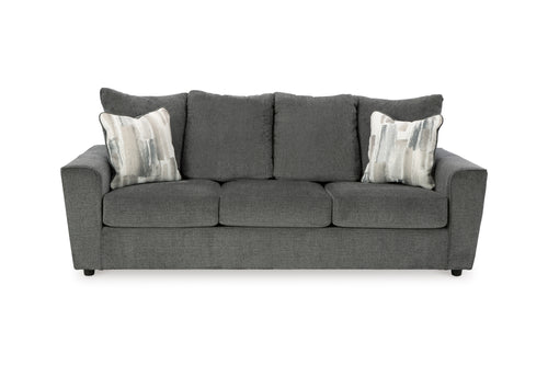 Sofá gris con cojines estampados sobre fondo blanco.