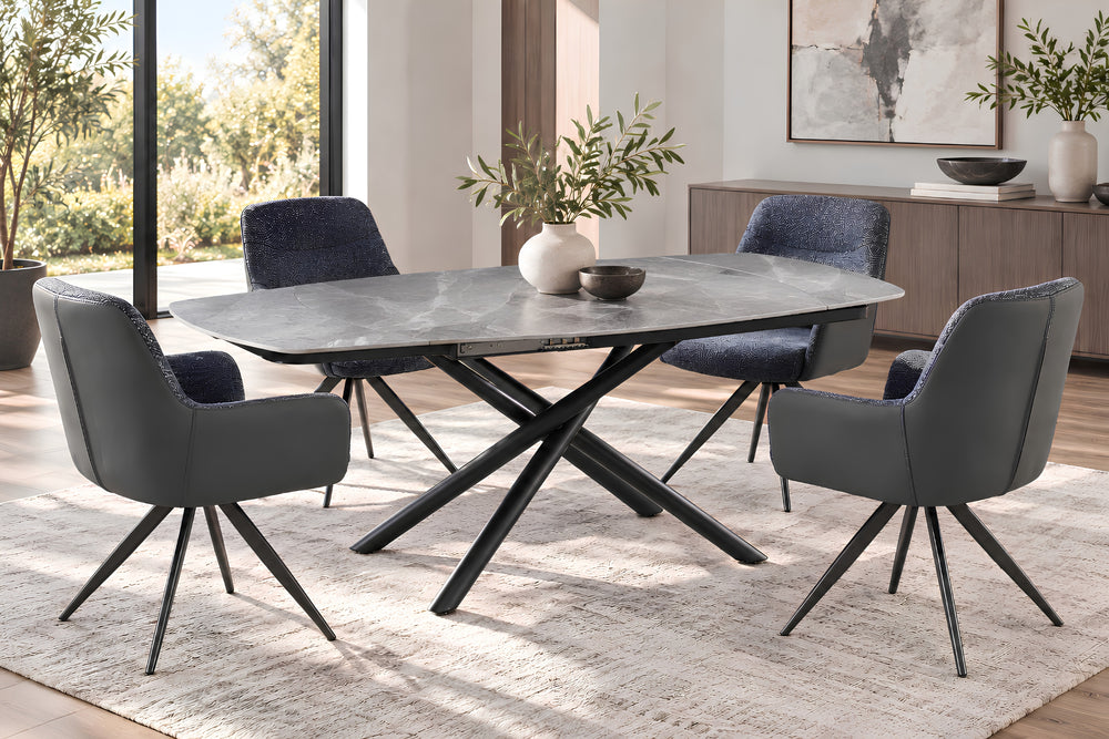 Juego de comedor moderno con mesa ovalada con tope gris y base en X negra, cuatro sillas tapizadas en gris con patas metálicas negras y una alfombra clara con textura en un comedor luminoso y contemporáneo