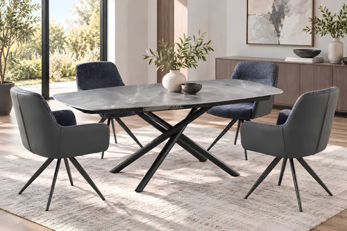 Juego de comedor moderno con mesa ovalada con tope gris y base en X negra, cuatro sillas tapizadas en gris con patas metálicas negras y una alfombra clara con textura en un comedor luminoso y contemporáneo