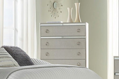 Chest de cinco gavetas de color plateado en una habitación moderna con elementos decorativos. 