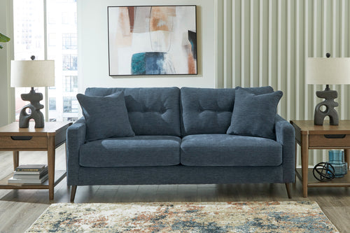 Sofá de color azul con patas acabadas en marrón en una sala moderna. 