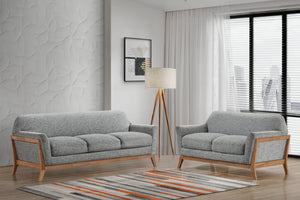 Sofá y loveseat de color gris en un ambiente de sala iluminada con objetos decorativos.