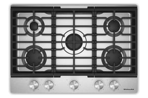 Un tope de cocina de gas de 5 quemadores con rejilla de hierro fundido negro y panel de control de acero inoxidable con cinco perillas plateadas, mostrada sobre un fondo blanco.