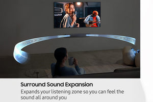 Persona viendo televisión con barra de sonido curva en una sala de estar. 