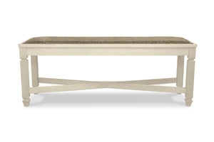 Un banco de madera natural clara con asiento tapizado en color topo texturizado, mostrado desde un ángulo de tres cuartos sobre un fondo blanco.