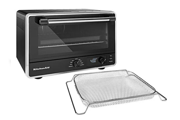 Horno de sobremesa KitchenAid en color negro y plateado con puerta de cristal, que se muestra junto a una rejilla de alambre de acero inoxidable sobre un fondo blanco.