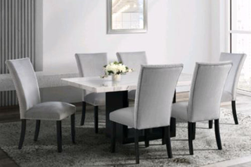 Mesa rectangular de diseño de mármol blanco y negro con seis sillas acolchados gris en una sala de comedor moderna con ventana. 