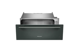 Cajón calentador KitchenAid de 30 pulgadas en color verde con acabado mate, mostrado parcialmente abierto para revelar el compartimento interior de acero inoxidable y la perilla de control lateral, sobre fondo blanco.