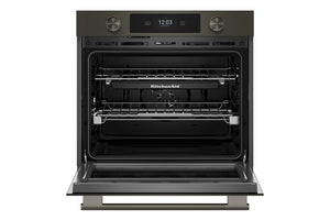 Un horno empotrado KitchenAid con exterior de color gris oscuro/negro y puerta de cristal abierta, que deja ver dos rejillas interiores y una pantalla de control digital.
