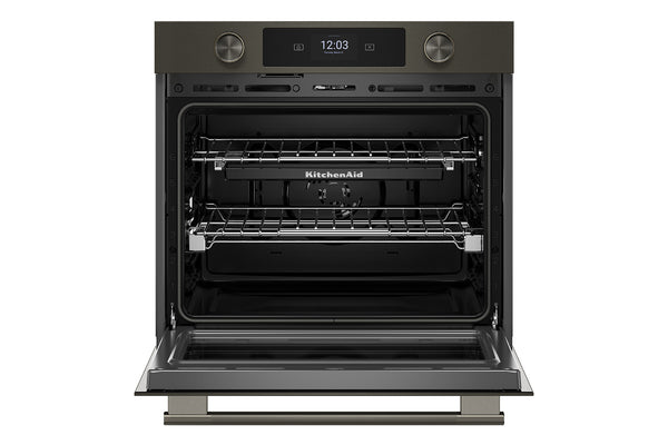 Un horno empotrado KitchenAid con exterior de color gris oscuro/negro y puerta de cristal abierta, que deja ver dos rejillas interiores y una pantalla de control digital.