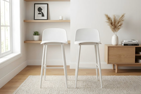 Dos taburetes blancos en una sala con estantes y decoración de madera.