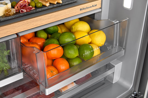 Gaveta de frutas en una nevera con naranjas, limas y limones, modelo KitchenAid.