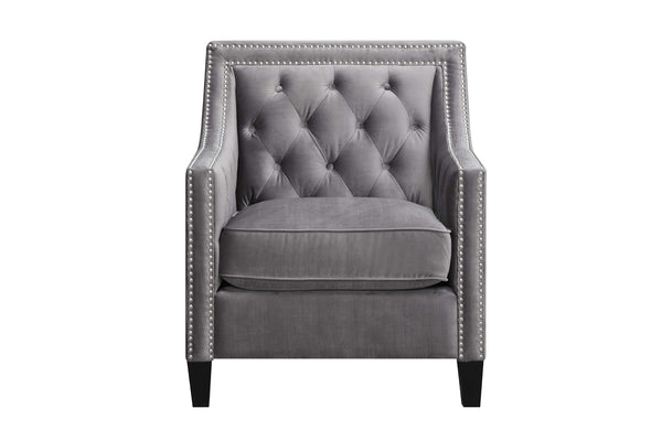 Butaca decorativa gris tapizada en tela aterciopelada, con respaldo capitonado con botones, brazos altos, detalles de tachuelas plateadas, asiento acolchado y patas negras sobre un fondo blanco.