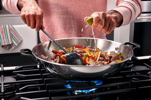 Persona cocinando un salteado en un wok sobre una estufa de gas.