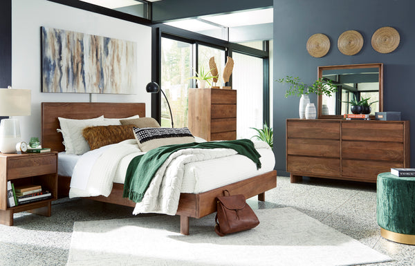 Dormitorio contemporáneo con cama de madera, mesa de noche, cómoda con espejo y cajonera alta a juego. La habitación incluye ropa de cama blanca, detalles decorativos en tonos verdes, arte mural y amplios ventanales que aportan luz natural.