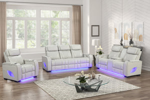 Juego de sala reclinable tapizado en cuero sintético blanco, compuesto por sofá, loveseat y sillón con costuras acolchadas, portavasos integrados e iluminación LED azul en la base, ubicado en una sala moderna y luminosa con mesa de centro de vidrio.
