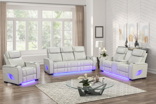 Juego de sala reclinable tapizado en cuero sintético blanco, compuesto por sofá, loveseat y sillón con costuras acolchadas, portavasos integrados e iluminación LED azul en la base, ubicado en una sala moderna y luminosa con mesa de centro de vidrio.
