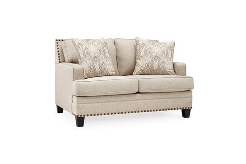 Loveseat de color crema con cojines decorativos sobre un fondo blanco. 