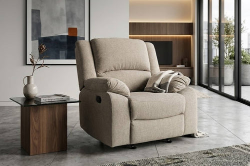 Una butaca reclinable tapizado en color beige con un cojín a juego, que se muestra en un salón moderno junto a una mesa auxiliar de madera.
