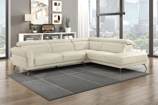 Seccional beige con patas acabadas en metal en una sala moderna con ventanas en el fondo. 