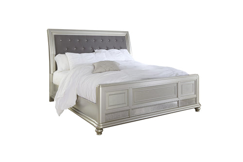 Cama plateada, capitoné, tapizada con acolchado blanco sobre fondo blanco.