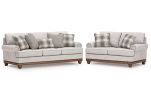 Sofás y loveseat gris claro con cojines a cuadros sobre un fondo blanco.
