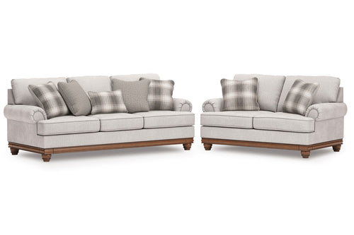 Sofás y loveseat gris claro con cojines a cuadros sobre un fondo blanco.