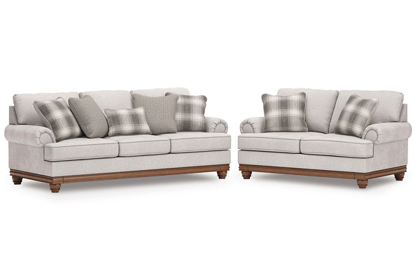 Sofás y loveseat gris claro con cojines a cuadros sobre un fondo blanco.