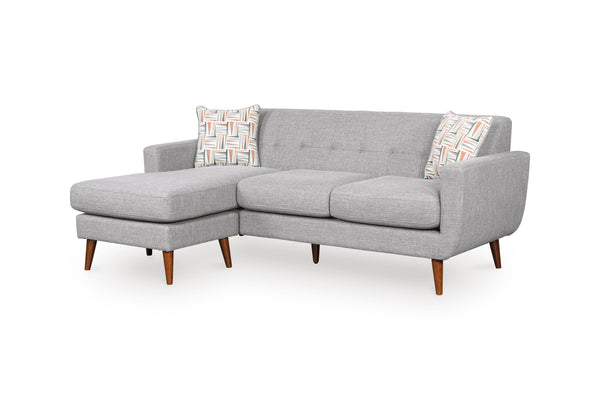 Sofa chaise de color gris claro con patas acabadas en madera y con dos cojines decorativos sobre un fondo blanco. 