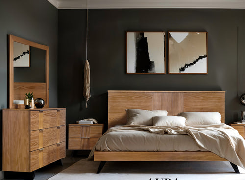 Una habitación moderna con cama de madera clara, cabezal de panel alto, mesa de noche a juego, gavetero con espejo beige frente a una pared de carbón oscuro con dos cuadros abstractos enmarcados.