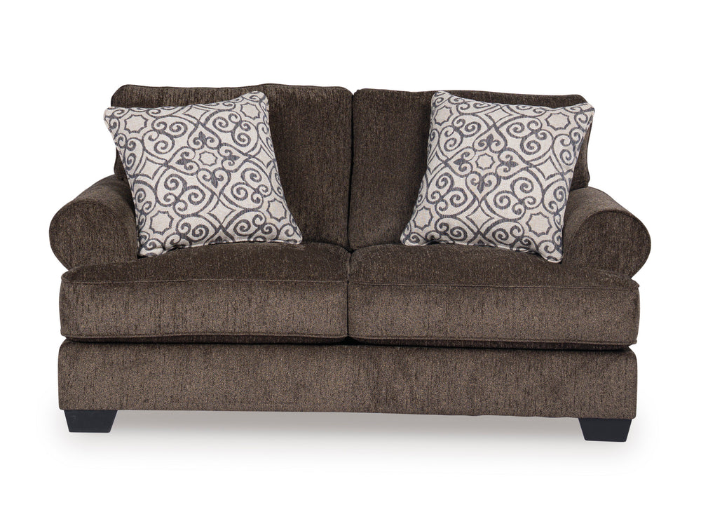 Loveseat marrón con cojines estampados sobre fondo blanco.