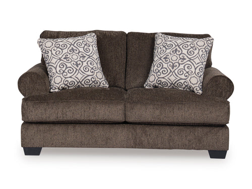 Loveseat marrón con cojines estampados sobre fondo blanco.