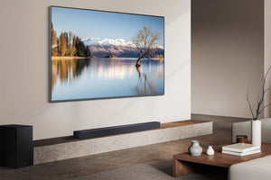 Televisor grande montado en una pared en una sala de estar con una barra de sonido debajo.