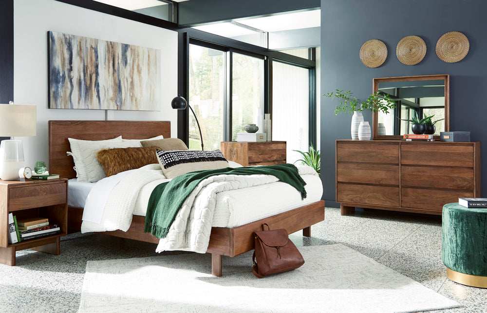 Dormitorio contemporáneo con cama de madera, mesa de noche, cómoda con espejo y cajonera alta a juego. La habitación incluye ropa de cama blanca, detalles decorativos en tonos verdes, arte mural y amplios ventanales que aportan luz natural.
