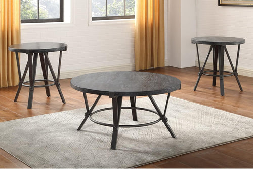 Mesa de centro redonda con tope de madera negra y base de hierro color gris en una sala neutral con dos otras mesas redondas en el fondo. 