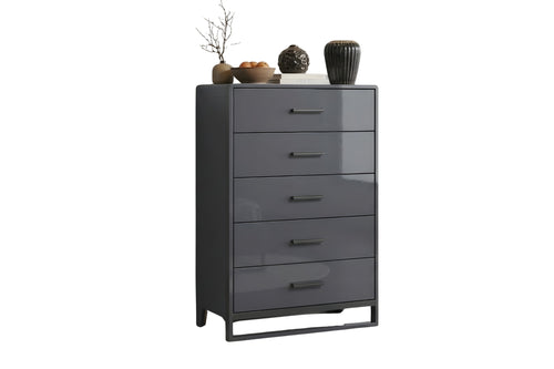 Chest de color gris oscuro con cinco gavetas y con objetos decorativos sobre un fondo blanco. 