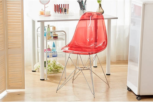 Silla roja transparente en una habitación con una mesa y varios objetos.