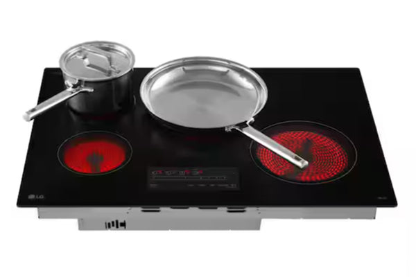 Tope de estufa negra de marca LG con cuatro quemadores y dos ollas encima de dos quemadores sobre un fondo blanco. 