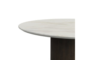 Primer plano de una mesa redonda con tablero de aspecto similar al mármol blanco y base oscura sobre un fondo blanco.